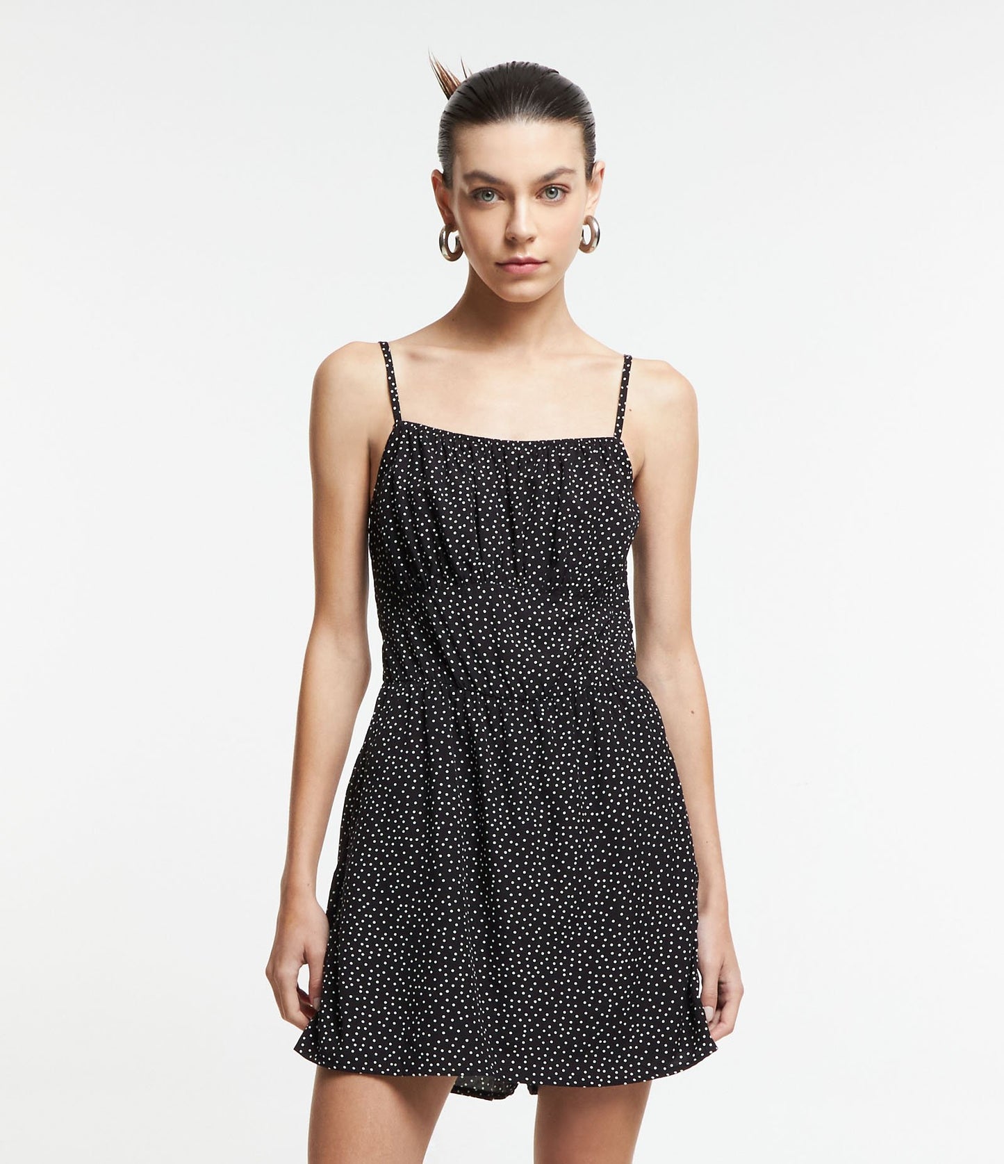 Macacão de viscose preto com bolinhas, alças e shorts com saia