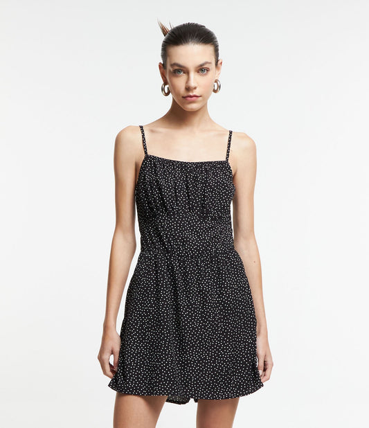 Macacão de viscose preto com bolinhas, alças e shorts com saia